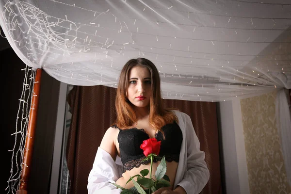 Bir beyaz erkek gömlek ve siyah sütyen reklam külot giymiş seksi kadın yatakta oturur