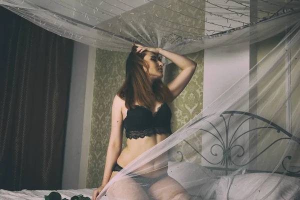 Bir beyaz erkek gömlek ve siyah sütyen reklam külot giymiş seksi kadın yatakta oturur