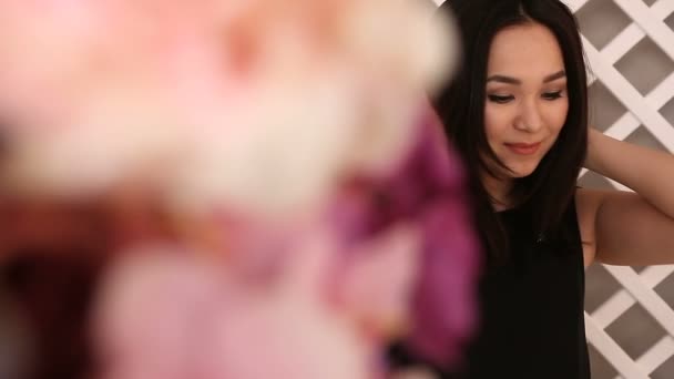 Νέοι όμορφο κορίτσι της Ασίας που ποζάρει στο παρασκήνιο, τα λουλούδια στο προσκήνιο — Αρχείο Βίντεο