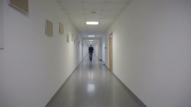Adam uzun beyaz koridorda gider