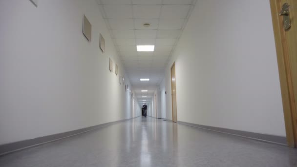 Young man runs through the white long hallway — Stock Video