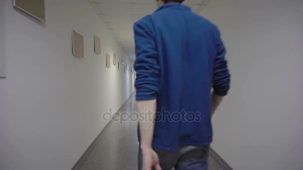 Molodj uomo porta via dlinnoo corridoio bianco — Video Stock