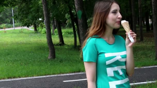 Linda mujer comiendo helado en el parque — Vídeo de stock