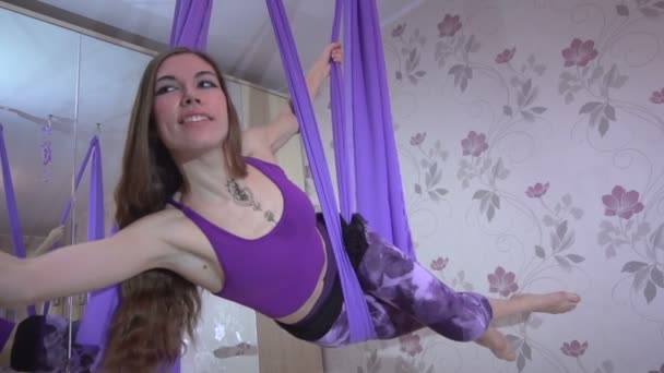 Привлекательная вдумчивая молодая женщина делает позы воздушной йоги с помощью гамака — стоковое видео