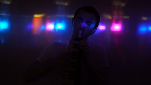 Een jonge man spelen de melodica in nachtclub — Stockvideo