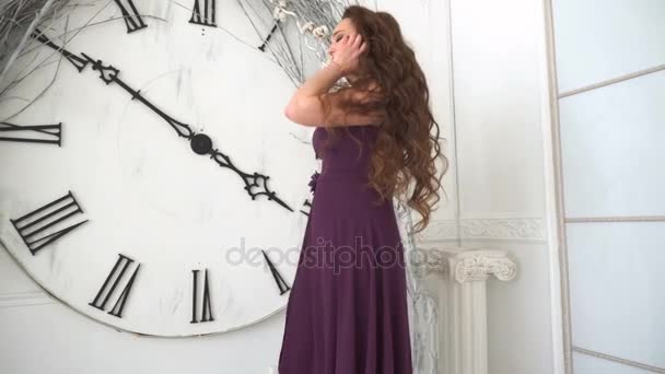 Chica en vestido de noche sonríe en el fondo grandes relojes de pared — Vídeos de Stock