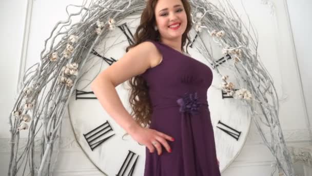 Chica en vestido de noche sonríe en el fondo grandes relojes de pared — Vídeos de Stock