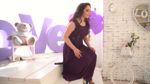 Елегантна дівчина в вечірній сукні, що стоїть на тлі великих літер кохання . — стокове відео