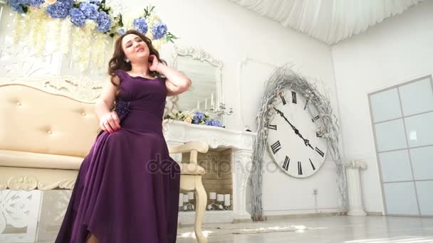 Young girl in an evening dress purple sitting on couch in luxury Interior — Stock Video