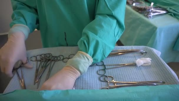 Chirurg in blauw handschoenen voorbereiding van instrumenten voor de operatie. Veeg van chirurgische klem. — Stockvideo