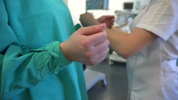 Krankenschwester hilft dem Chirurgen, medizinisches Gewand zu tragen — Stockvideo