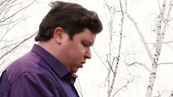 Homem gordo irritado com fone de ouvido ao ar livre — Vídeo de Stock