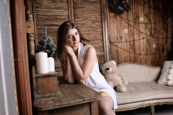 Krásná dívka sedí v místnosti dřevěným interiérem a čekání na Vánoce Stock Snímky