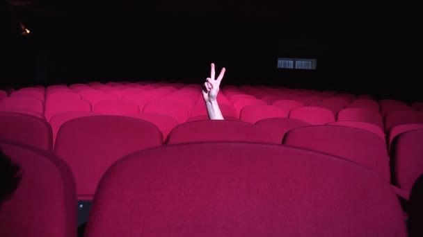 Closeup mans hand showing victory v sign between the rows of red chairs — Stock Video