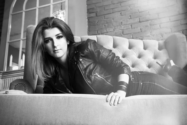 Çekici kız kanepede yatan yüksek pompalar ile deri ceketli