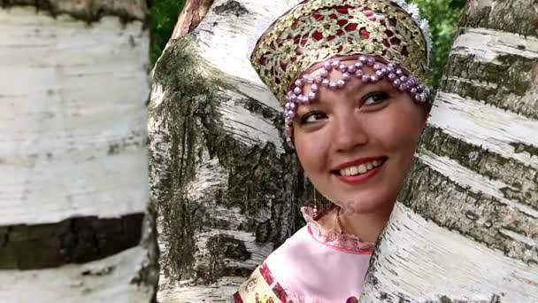 Happy russian girl in folk costume and birch — Stock Video