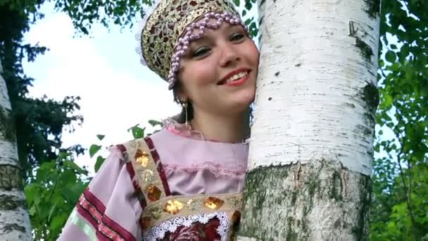 Русская девушка в народном костюме мечтает о березе — стоковое видео
