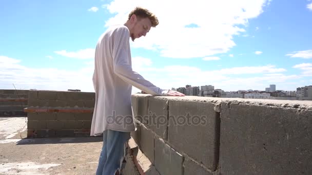 红头发的年轻男子，站在屋顶上的城市景观和蓝色天空背景 — 图库视频影像