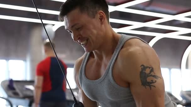 Joven culturista haciendo el ejercicio para los tríceps en el gimnasio — Vídeos de Stock