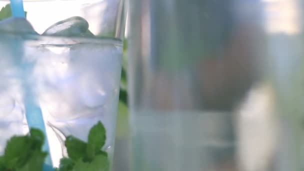 Agua mineral en el vaso con cubitos de hielo, menta, lima y rodajas de limón en el festival de comida callejera — Vídeo de stock