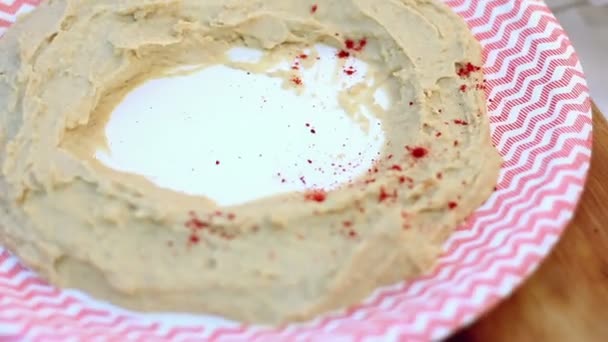 Traditionell arabisk maträtt hummus, beströs med paprika. — Stockvideo