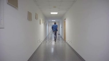 Bir adam uzun bir koridordan çalışır