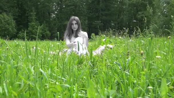 De geest van een jonge vrouw zittend op het gras in het park — Stockvideo