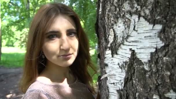 Jonge vrouw poseren in een park in de buurt van birch tree — Stockvideo