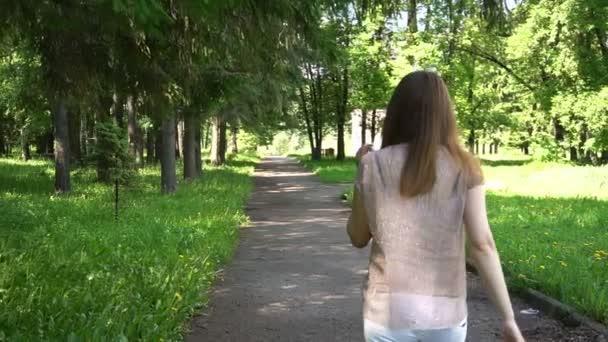 Joven caucásico atractivo sonrisas mujer camina en el parque — Vídeos de Stock