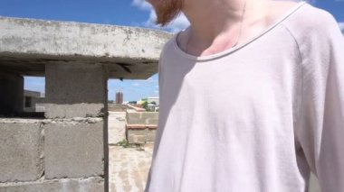 Kızıl saçlı genç adam çatıda cityscape ve mavi gökyüzü arka plan üzerinde ayakta