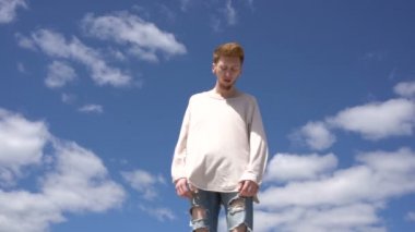 Sakallı yakışıklı delikanlı gökyüzü arka plan üzerinde kamera için poz veriyor