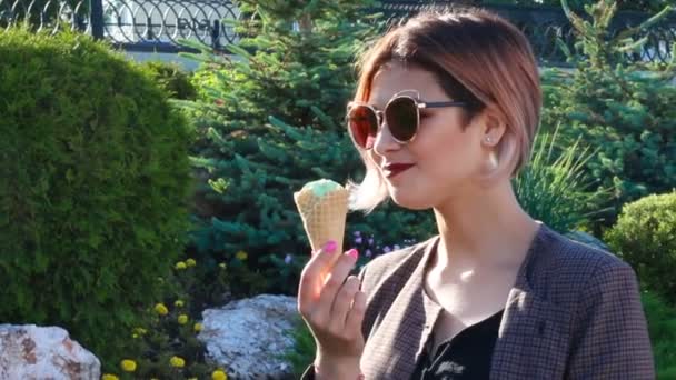 Όμορφο κομψό κορίτσι σε γυαλιά ηλίου τρώει παγωτό σε κώνο — Αρχείο Βίντεο