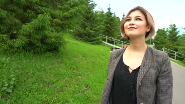 Slow Motion gelukkig lachende jonge vrouw in jas rondlopen in zonnig park op zomers dag. — Stockvideo
