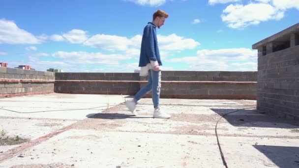 Young red-haired man hides from the sun in the shade on the roof. — Stock Video