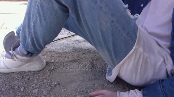 Рудий модний молодий чоловік сидить на підлозі даху в джинсовому одязі і рвані джинси — стокове відео