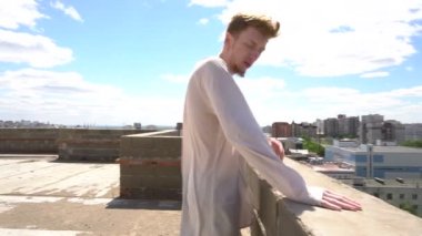 Kızıl saçlı genç adam çatıda cityscape ve mavi gökyüzü arka plan üzerinde ayakta