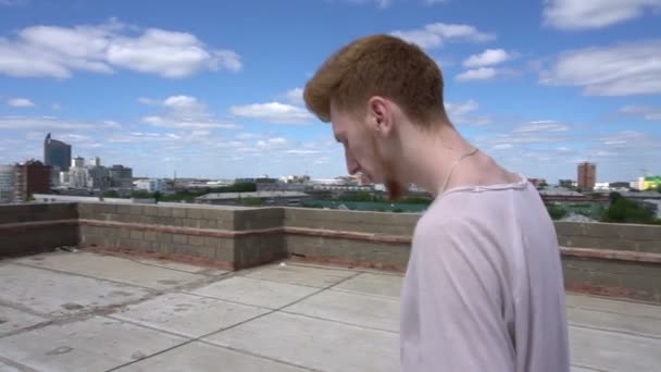 Man lopen op dak heen en weer langs het hek op de achtergrond van de hemel — Stockvideo