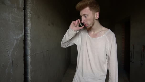 Человек с рыжими волосами разговаривает по телефону — стоковое видео