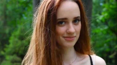 güzel bir genç kadın yakın çekim, yeşil yaz Park karşı gülümseyen portresi