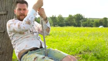 Bir salıncak üzerinde sakallı yakışıklı sakallı adam