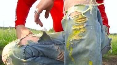 Şık yırtık kot pantolon ve açık kırmızı kapüşonlu adam sakallı