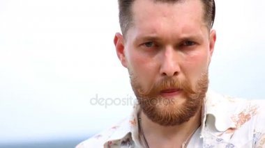 Açık havada kameraya bakarak tişörtlü çekici genç sakallı adam portresi