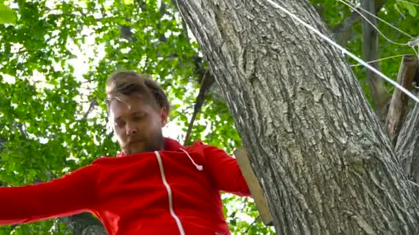 Cool muž v červených sedí na stromě — Stock video