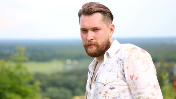 Portrait of attractive young bearded man in shirt looking at the camera outdoors — Stock Video