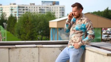Sakallı adam açık havada telefonu konuşurken