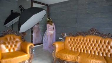 Genç hamile modeli Aynaya bakar ve fotoğraf çekimi için gider