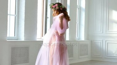 Hamile genç kadın soyunma sabahlığı pencerenin önünde duruyor