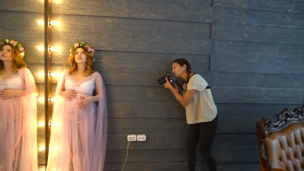Bella giovane modello di foto incinta in lilla peignoir posa per fotografo femminile . — Video Stock