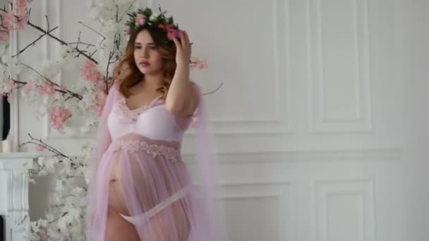 Gravida vacker flicka i lila peignoir och blommig huvud krans går på lyxrum — Stockvideo