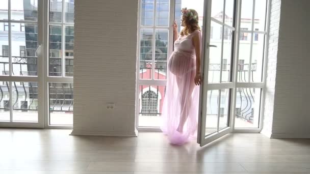 Профиль беременной девушки с длинными каштановыми волосами, смотрящей на городской пейзаж с балкона — стоковое видео